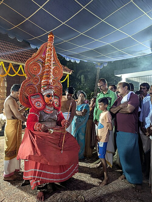 Bhairavan Theyyam at Cherakkara Tharavad, Kanhangad — a Bhairavan Theyyam performer in full ritual vesham and Mudi headgear at a tharavad kavu in Kanhangad, Kasaragod district, Kerala, showing the intense facial expression, elaborate costume, and characteristic upright posture of the divine embodiment that occurs when the Mudi is placed and the deity is believed to enter the performer's body