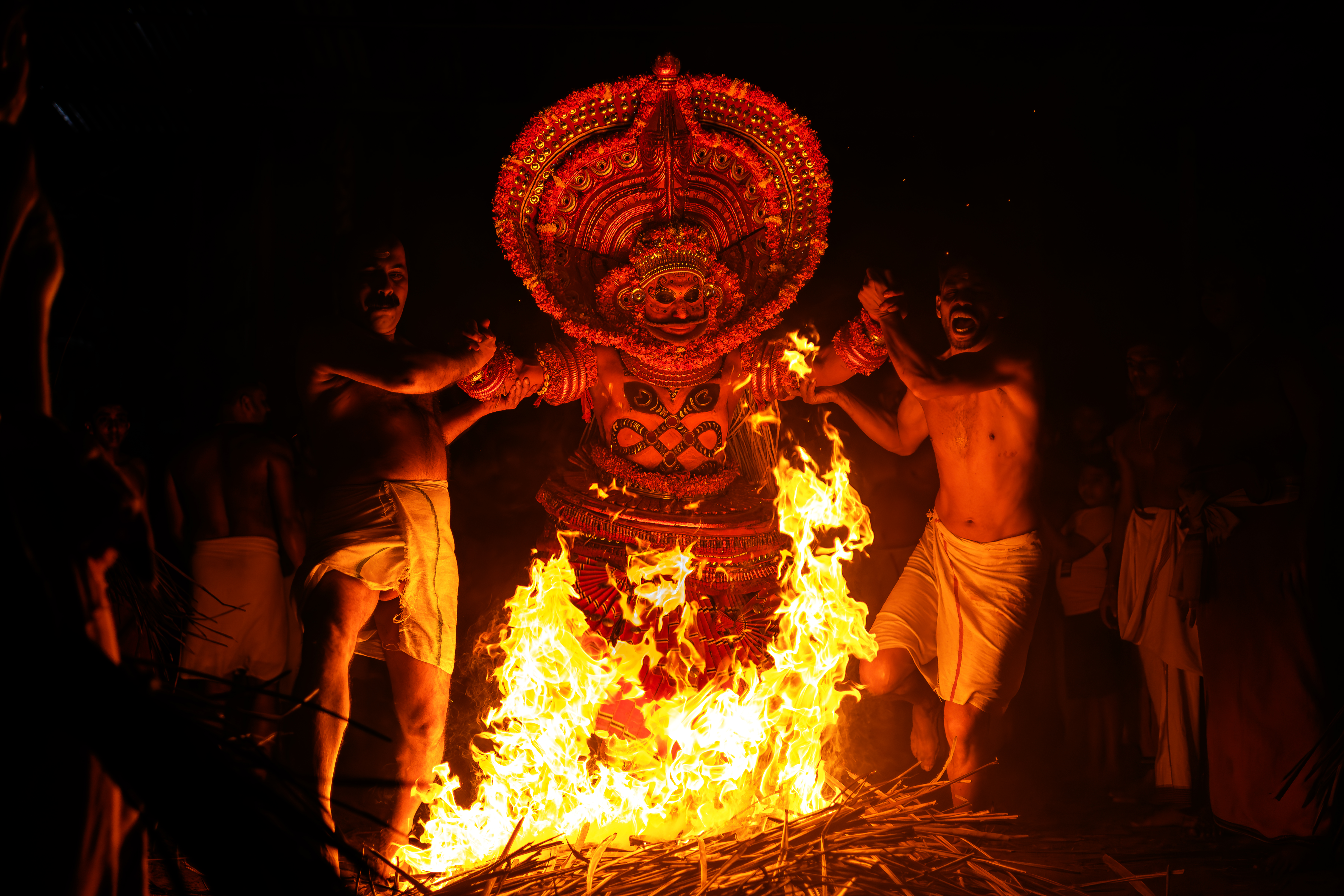 Kandanar Kelan Theyyam in full performance at Kannur, Kerala — the fire deity in elaborate silk costume with serpents on chest, one of North Kerala's most dramatic Theyyam forms
