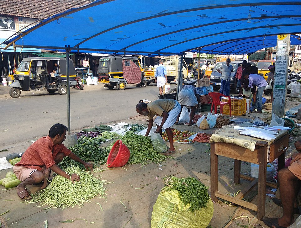 Vegetable market at Thrissur, Kerala — the traditional Chantha gathering where farmers bring their produce directly to buyers, setting prices through direct negotiation in a public space that combines commerce, news, social interaction, and community identity in a single weekly event